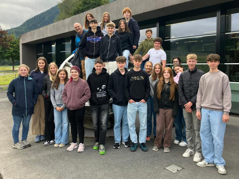 Klassenfoto vor dem Kraftwerk, einige Schüler:innen sind auf die Turbinen geklettert